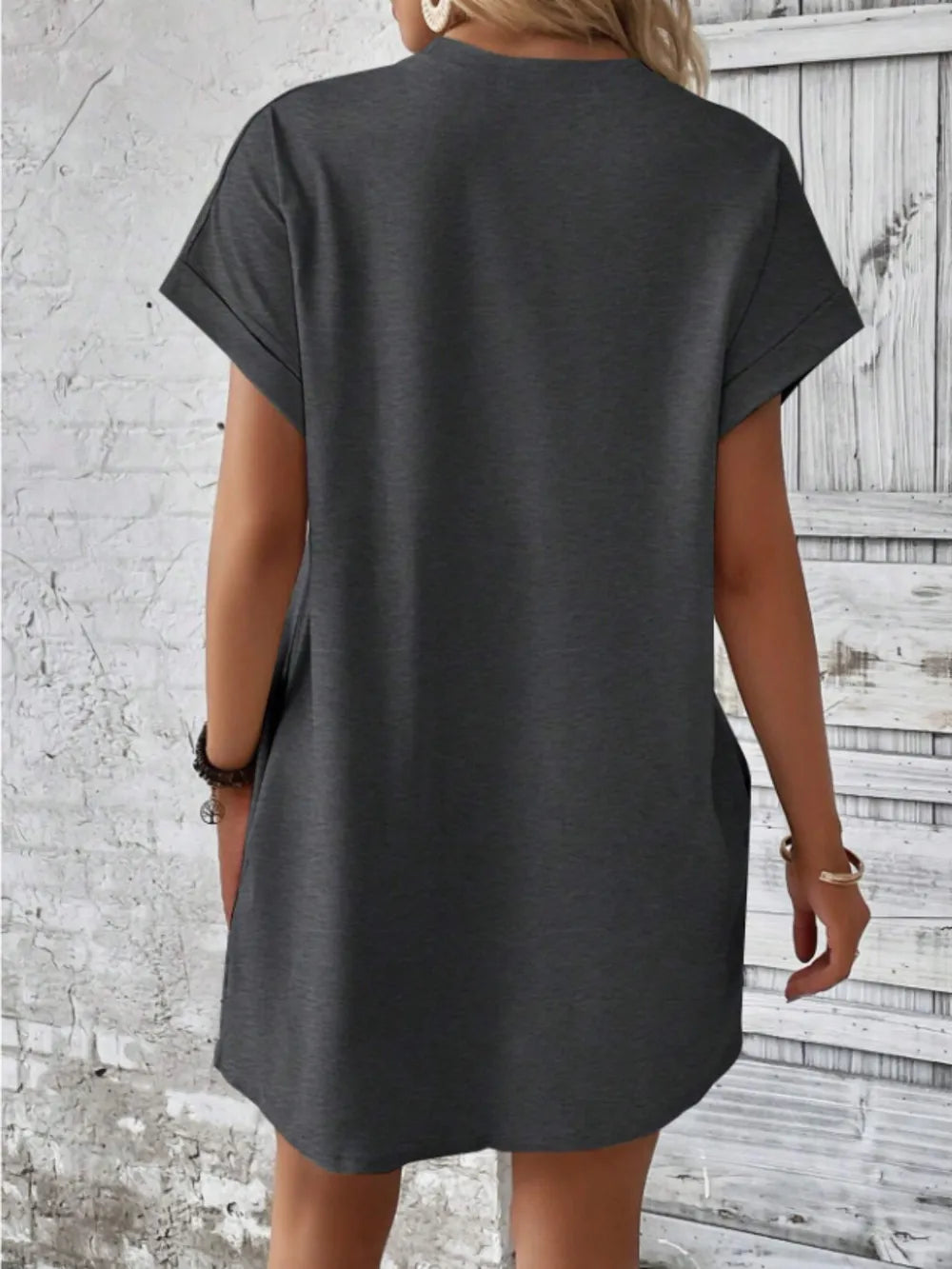 Person wearing a dark gray t-shirt against a textured wall.