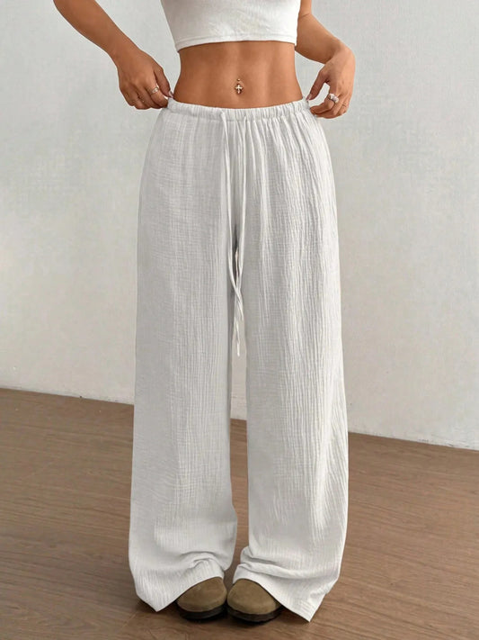 Person wearing white wide-leg pants on a plain background