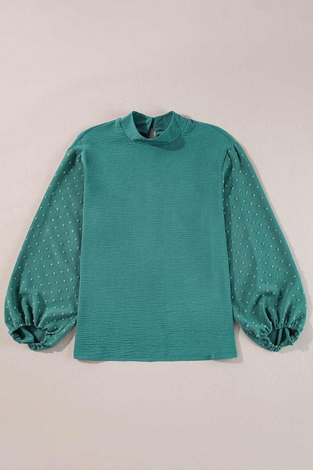 Green blouse with long sleeves on a beige background