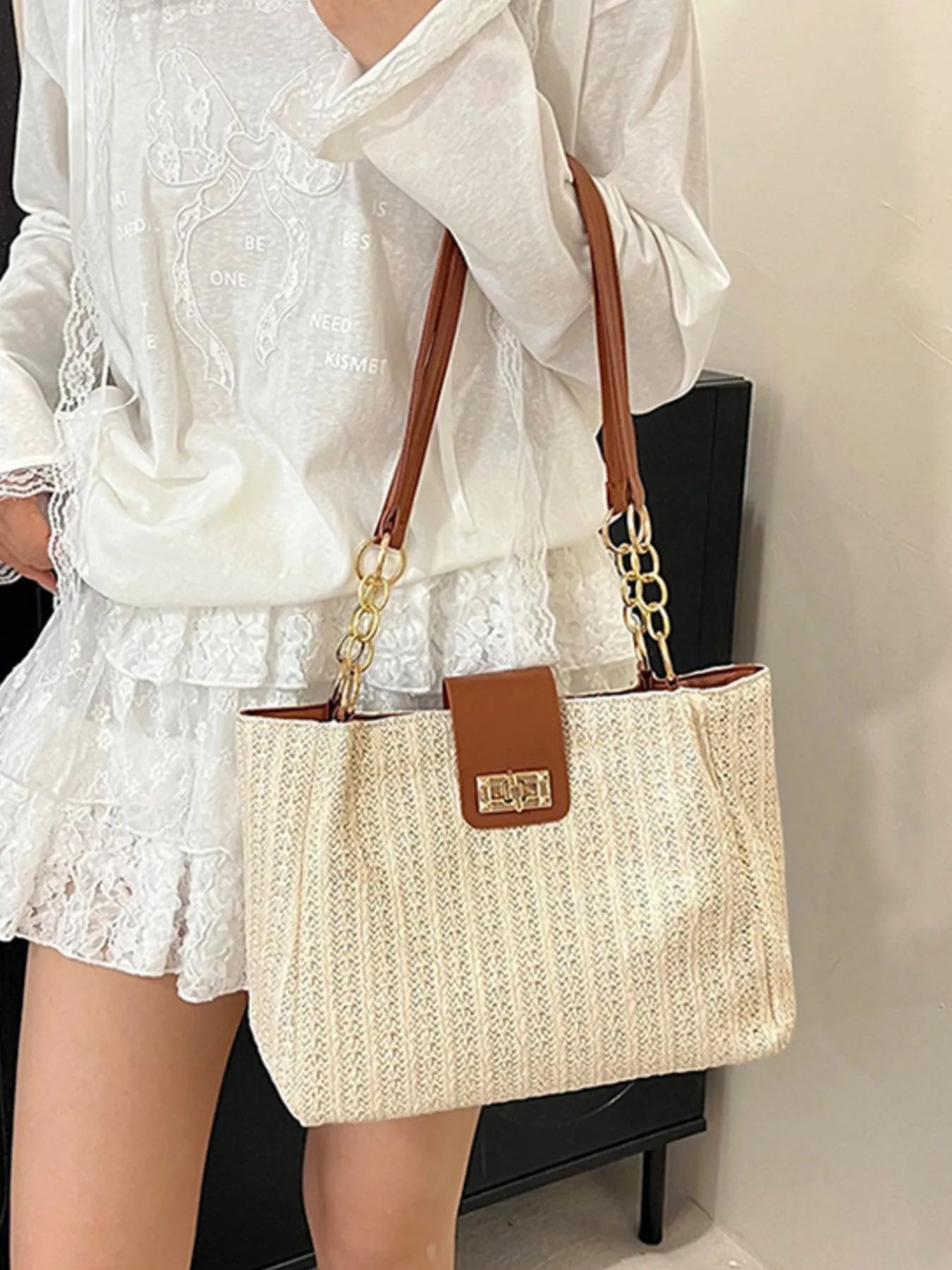 Person holding a beige handbag with brown accents against a neutral background
