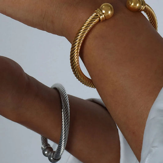 Gold and silver bracelets on a wrist against a white background