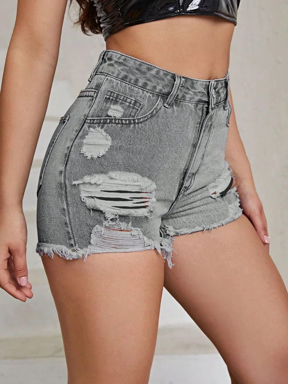 Gray distressed denim shorts worn by a person on a neutral background