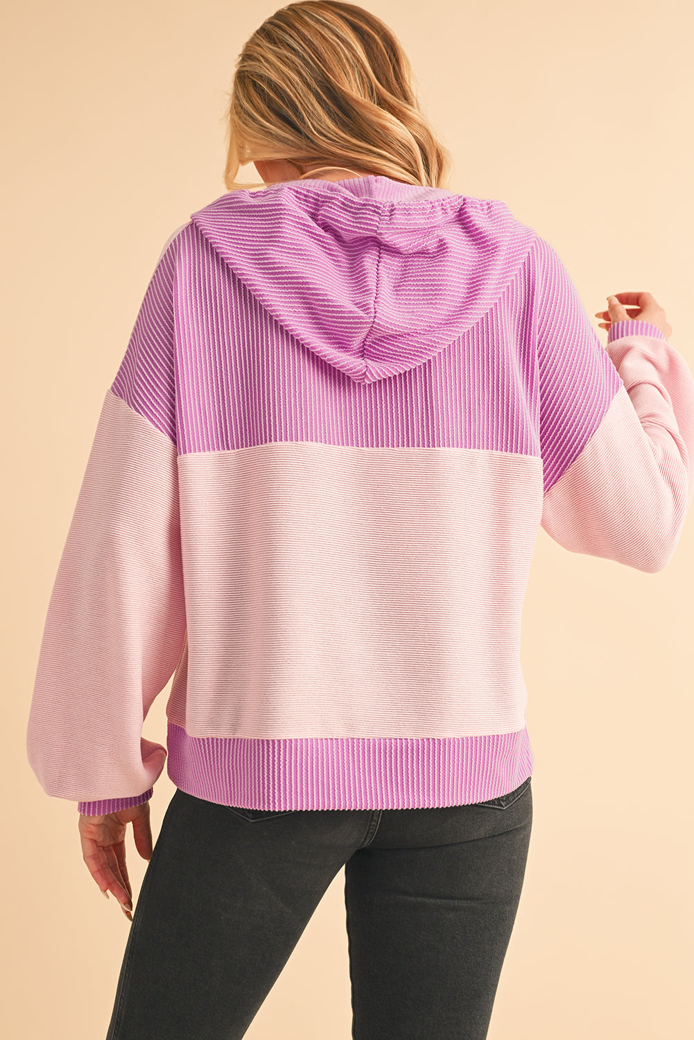 Person wearing a pink and purple striped hoodie on a beige background