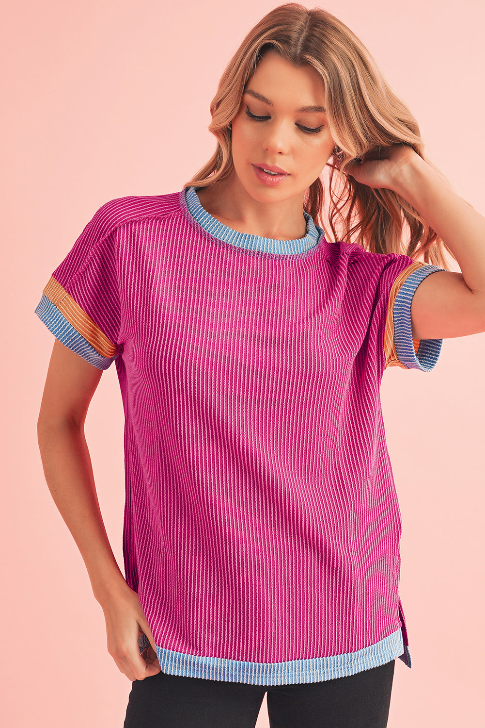 Woman wearing a pink ribbed knit top with colorful sleeves against a pink background