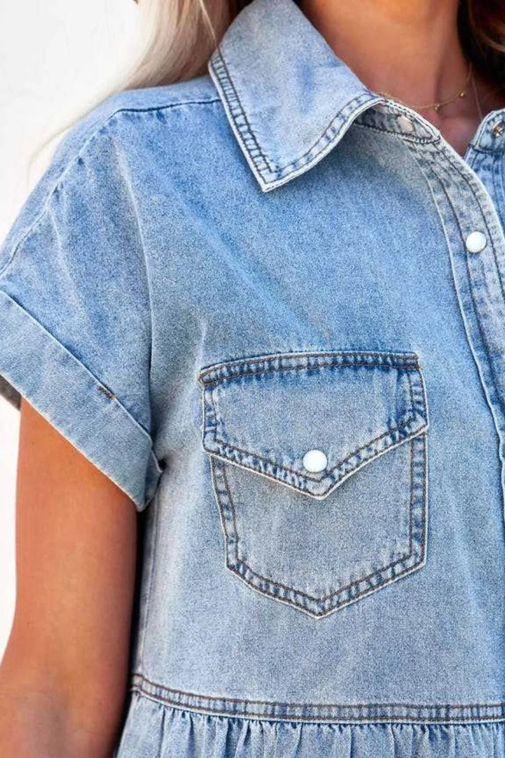 Close-up of a blue denim dress with a pocket on a white background