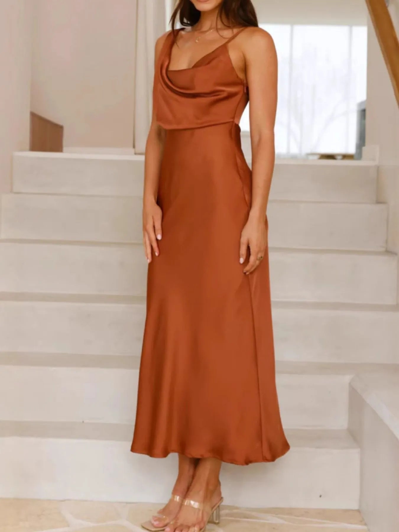 Woman wearing a rust-colored dress standing on a staircase.
