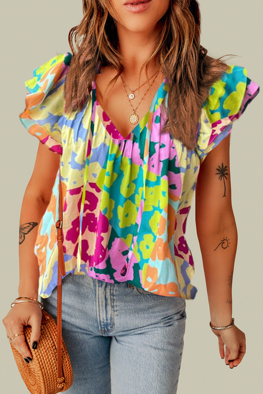 Woman wearing a colorful floral blouse with denim jeans on a neutral background