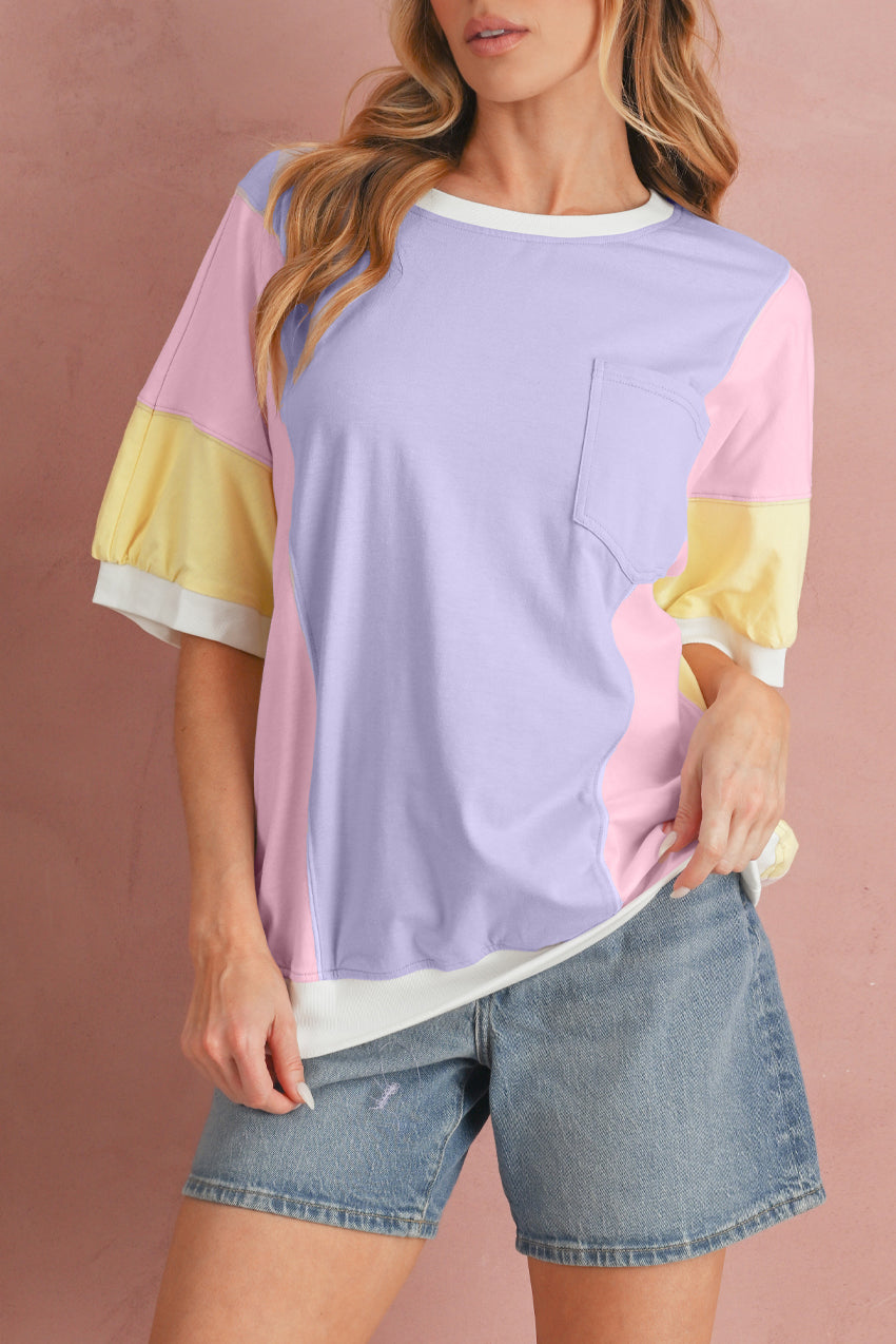 Woman wearing a pastel color-blocked shirt with denim shorts on a pink background