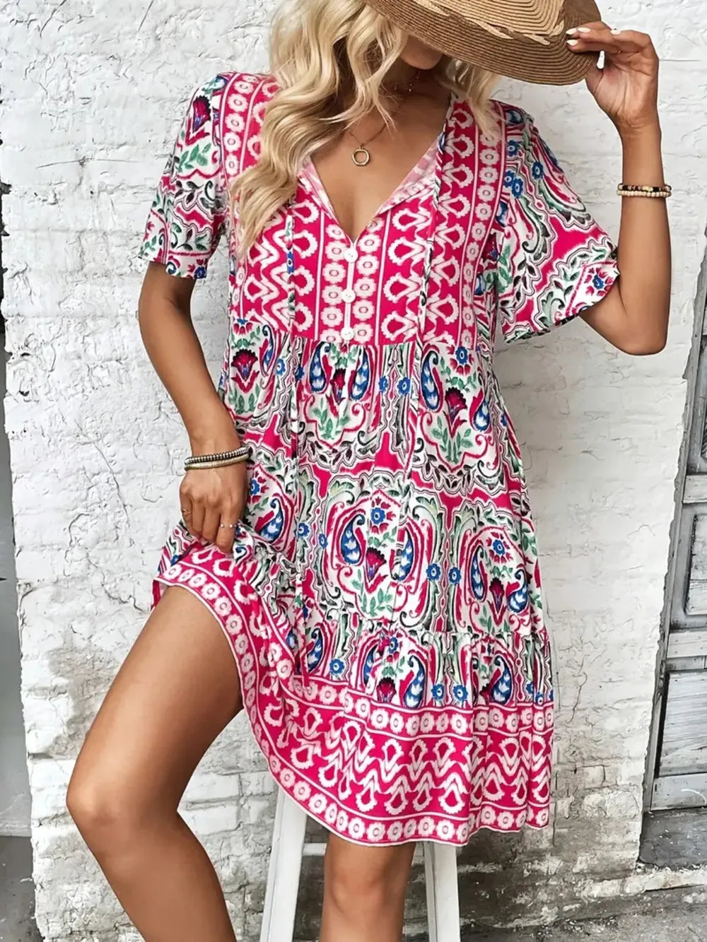 Woman wearing a colorful patterned dress with a white brick wall background