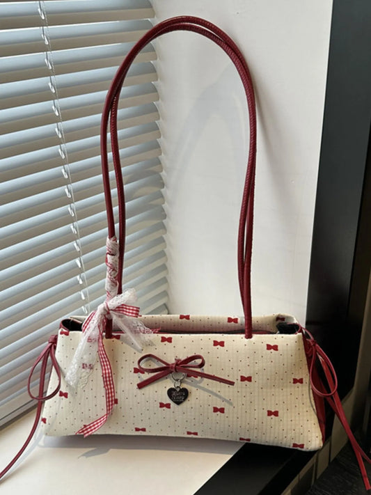 Handbag with red handles and decorative elements on a surface near a window with blinds.