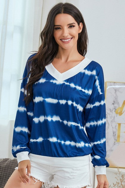 Woman wearing a blue and white tie-dye long-sleeve top in a room.