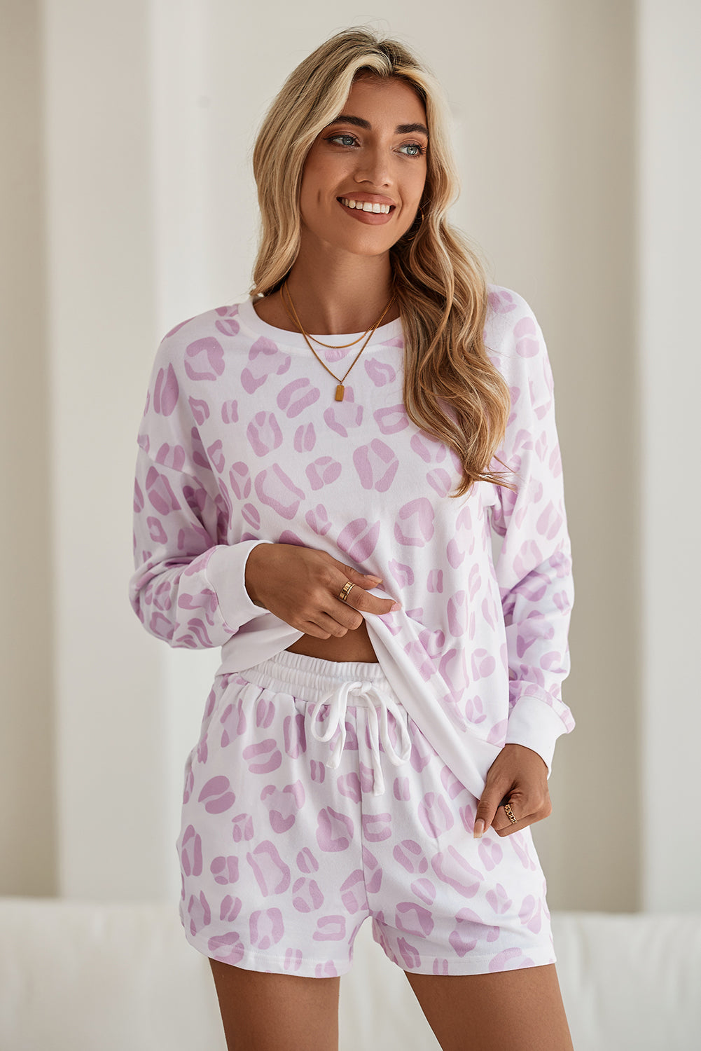 Woman wearing a pink leopard print pajama set against a neutral background