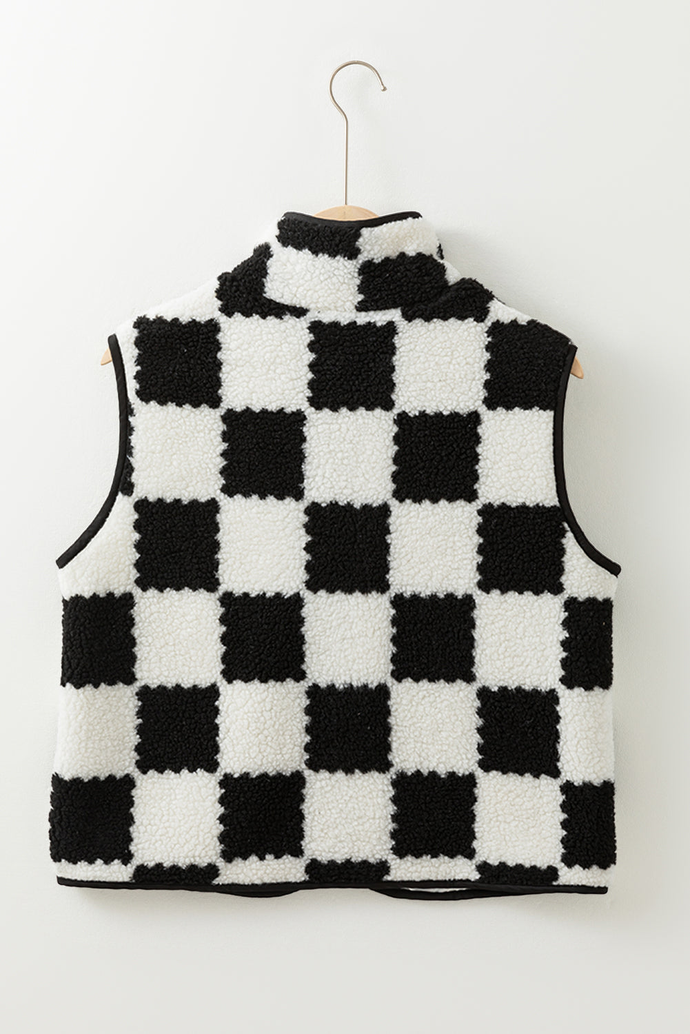 Black and white checkered sleeveless sweater on a hanger against a white background