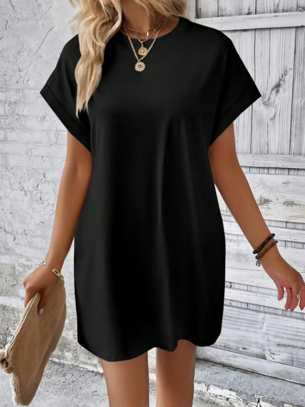 Woman wearing a black dress against a textured wall background