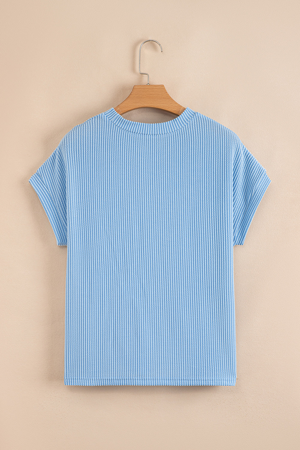 Blue striped t-shirt on a wooden hanger against a beige background