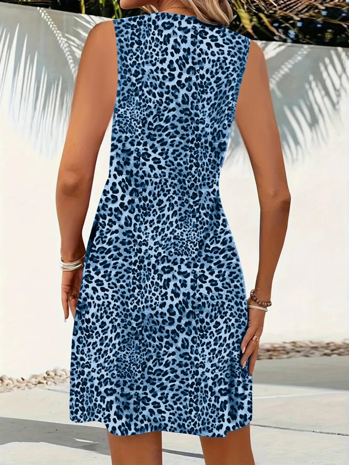 Person wearing a blue leopard print dress with a blurred beach background