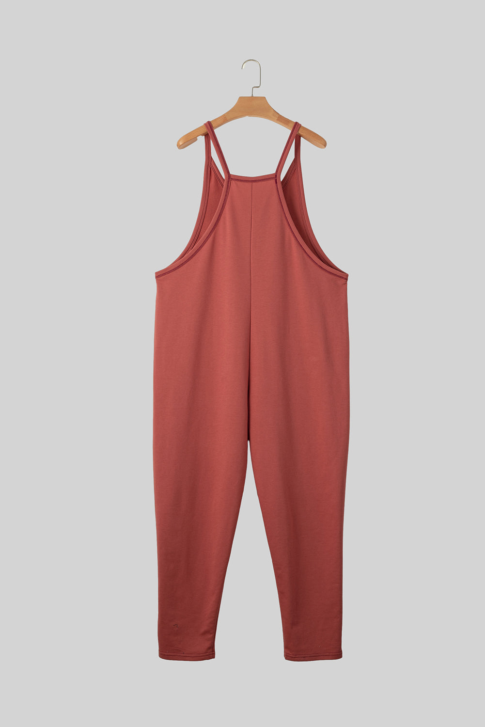 Red jumpsuit on a hanger against a gray background