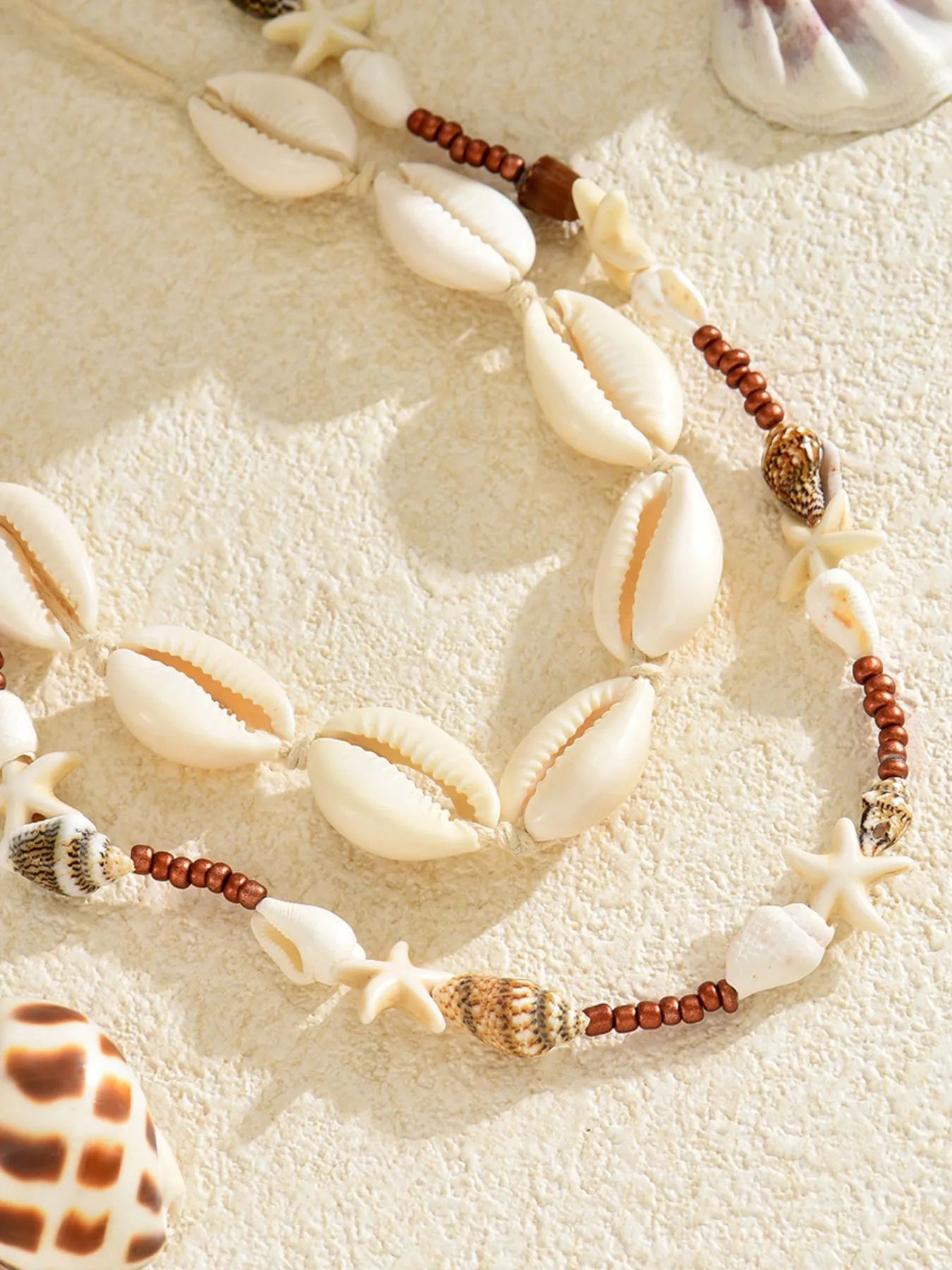 Necklace with seashells and beads on a sandy surface