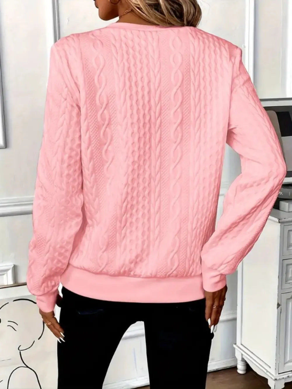 Person wearing a pink textured sweater in an indoor setting