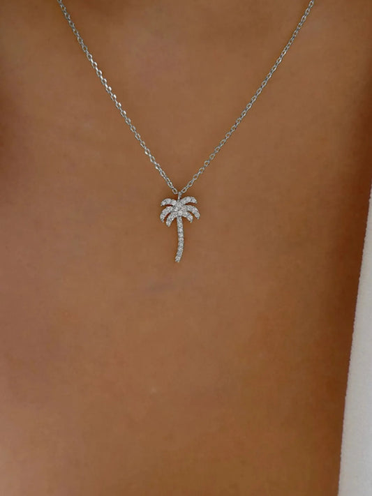 Silver palm tree necklace on a brown background