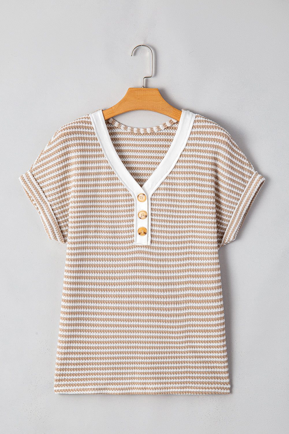 Striped shirt with buttons on a hanger against a gray background