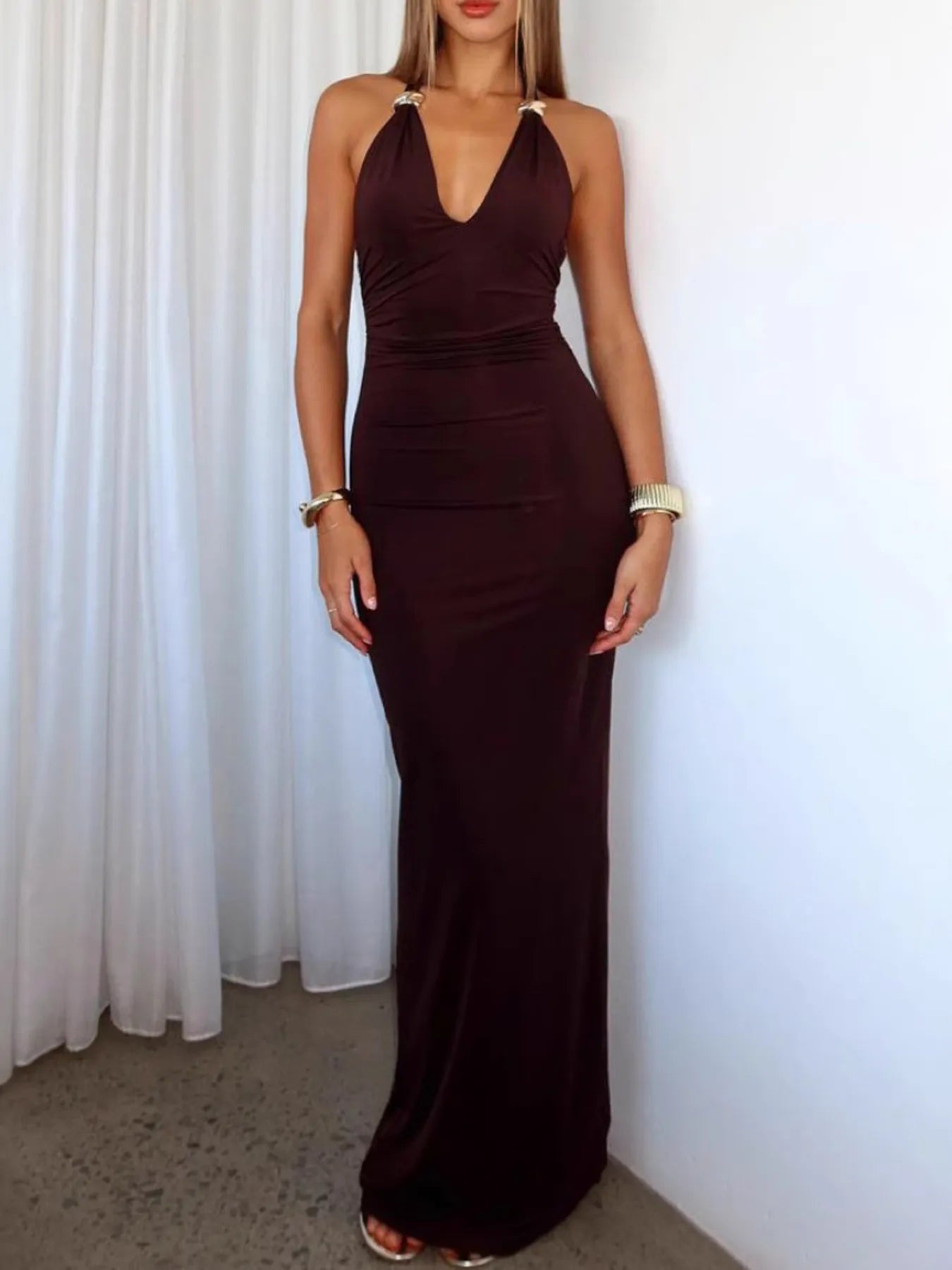Woman wearing a brown halter neck dress against a white curtain background