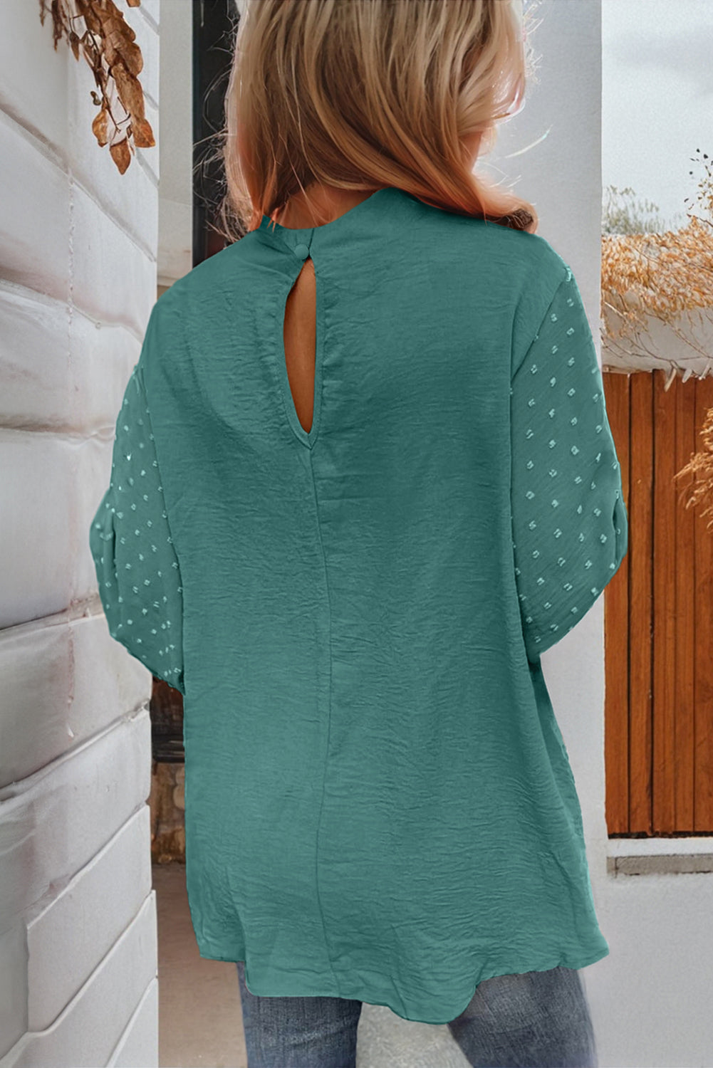 Person wearing a teal blouse with a cut-out back design.