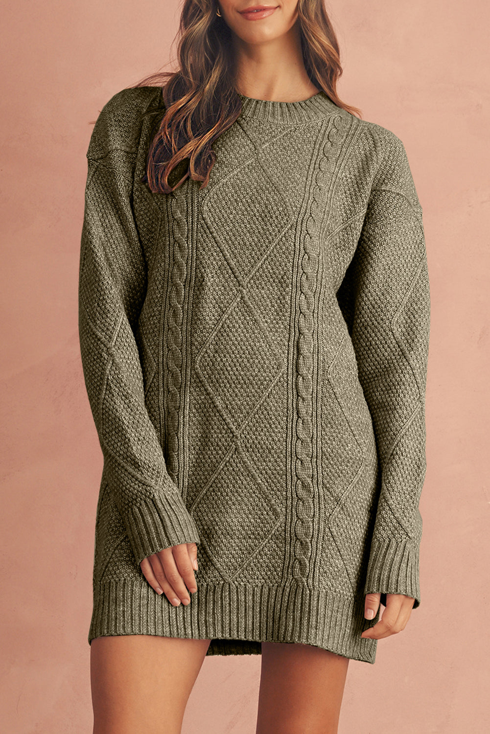Person wearing a green cable knit sweater dress against a beige background