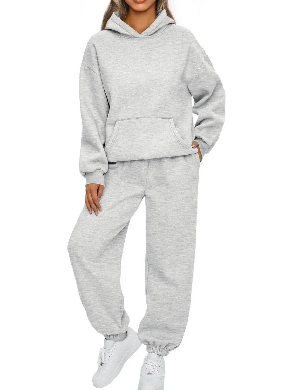 Person wearing a gray hoodie and sweatpants set on a white background