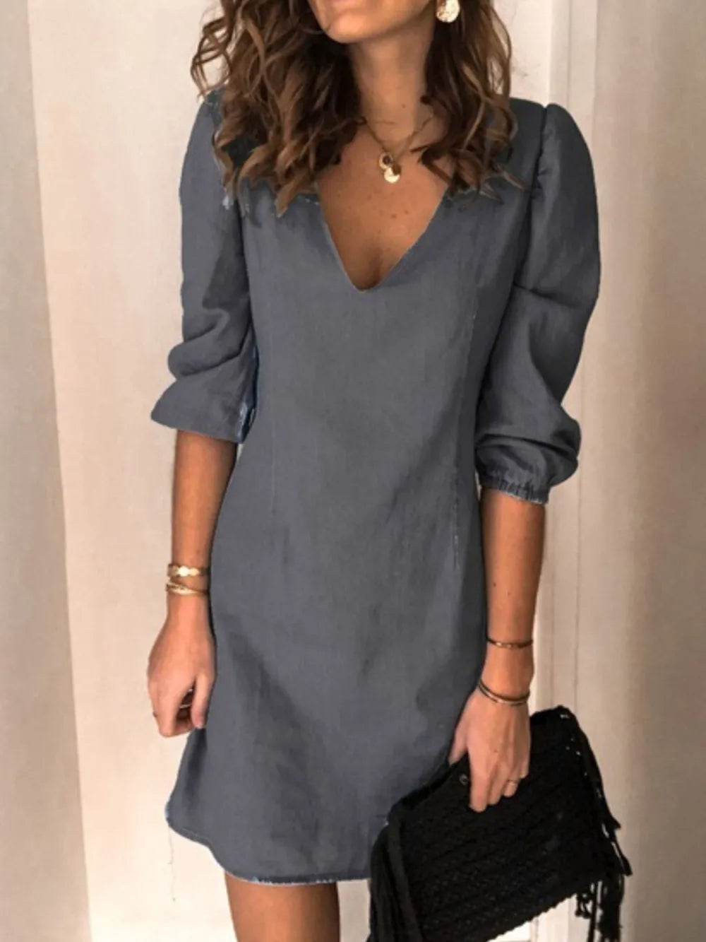 Woman wearing a blue dress with long sleeves against a neutral background