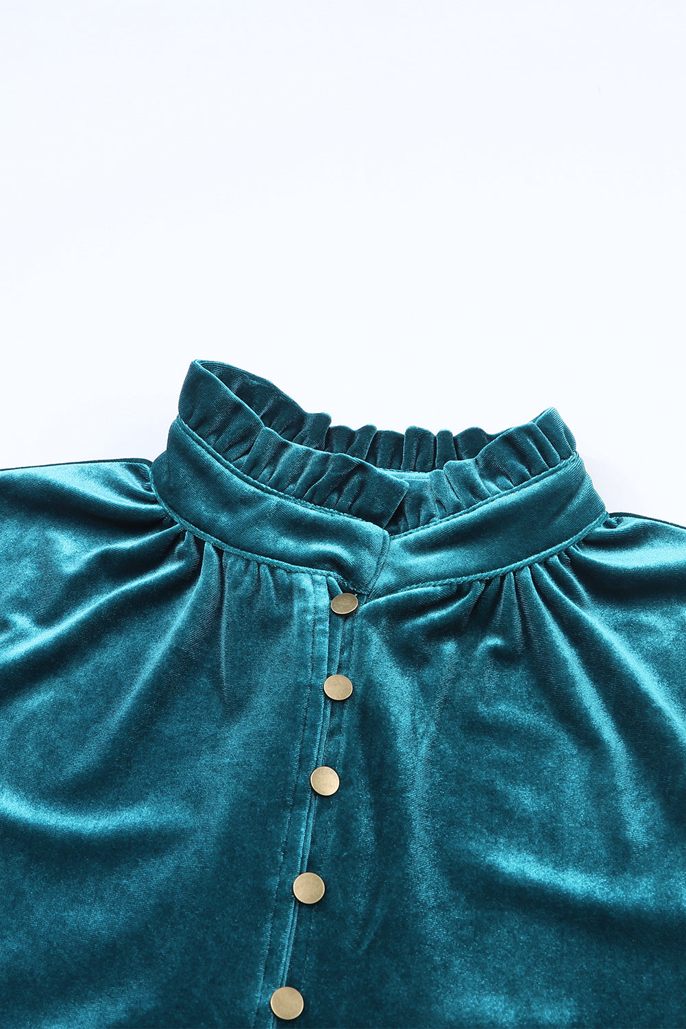 Teal velvet garment with button details on a light blue background
