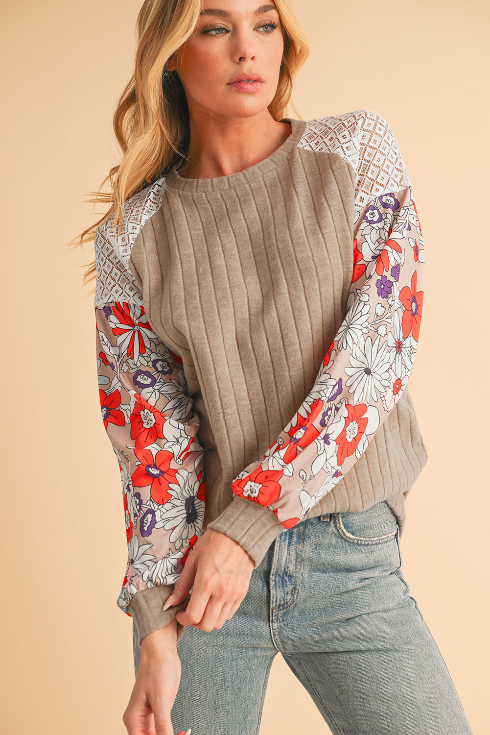 Woman wearing a beige sweater with floral sleeves on a beige background