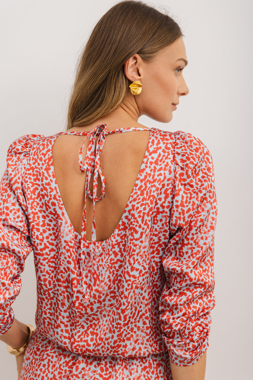 Woman wearing a red and white patterned blouse with a open back design.