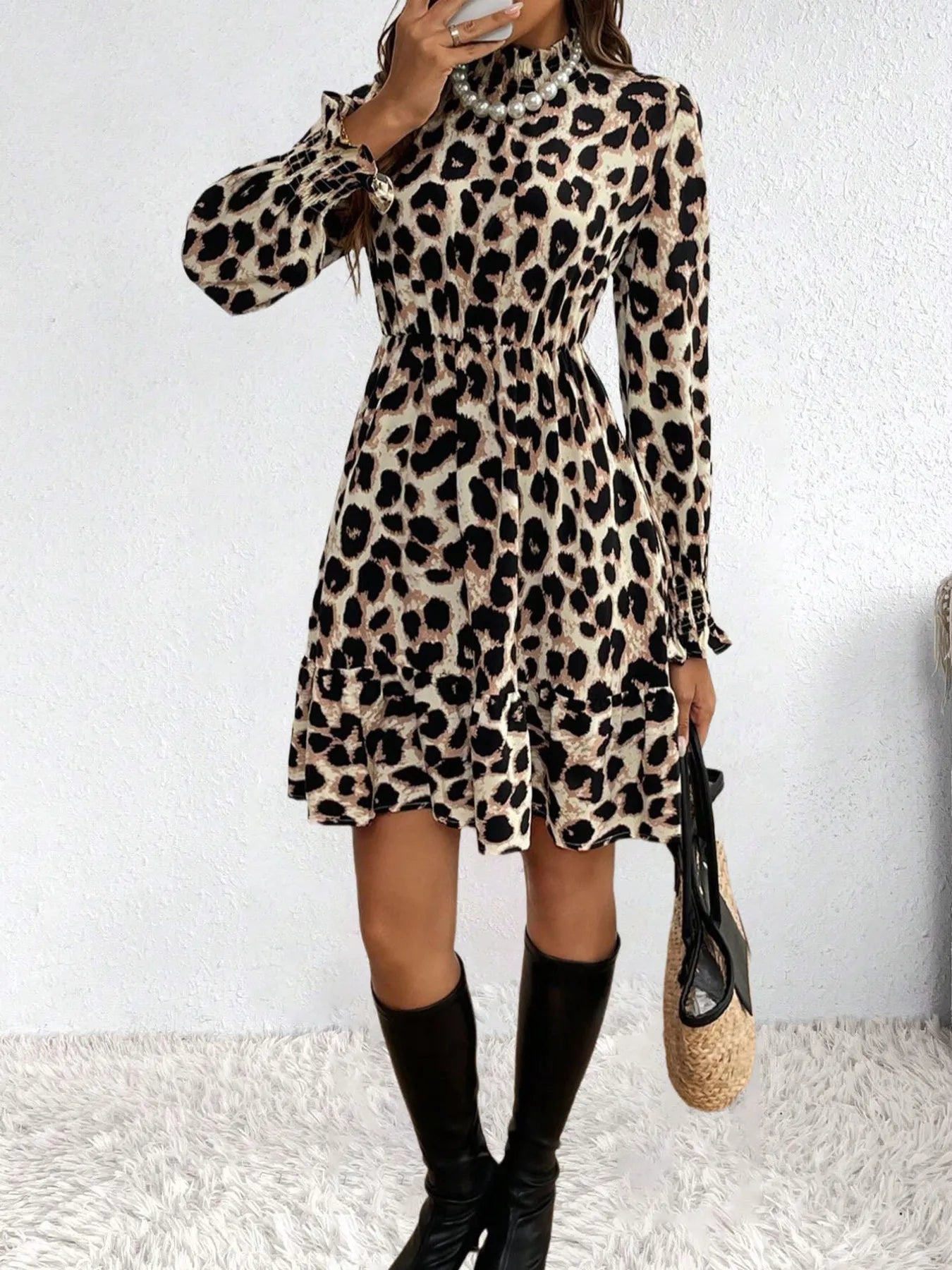 Person wearing a leopard print dress with long sleeves against a white background
