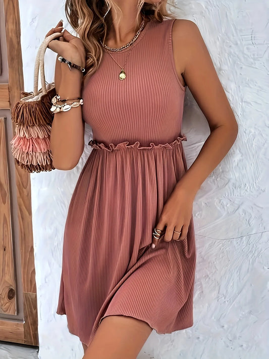 Woman wearing a pink dress holding a woven bag against a white wall.