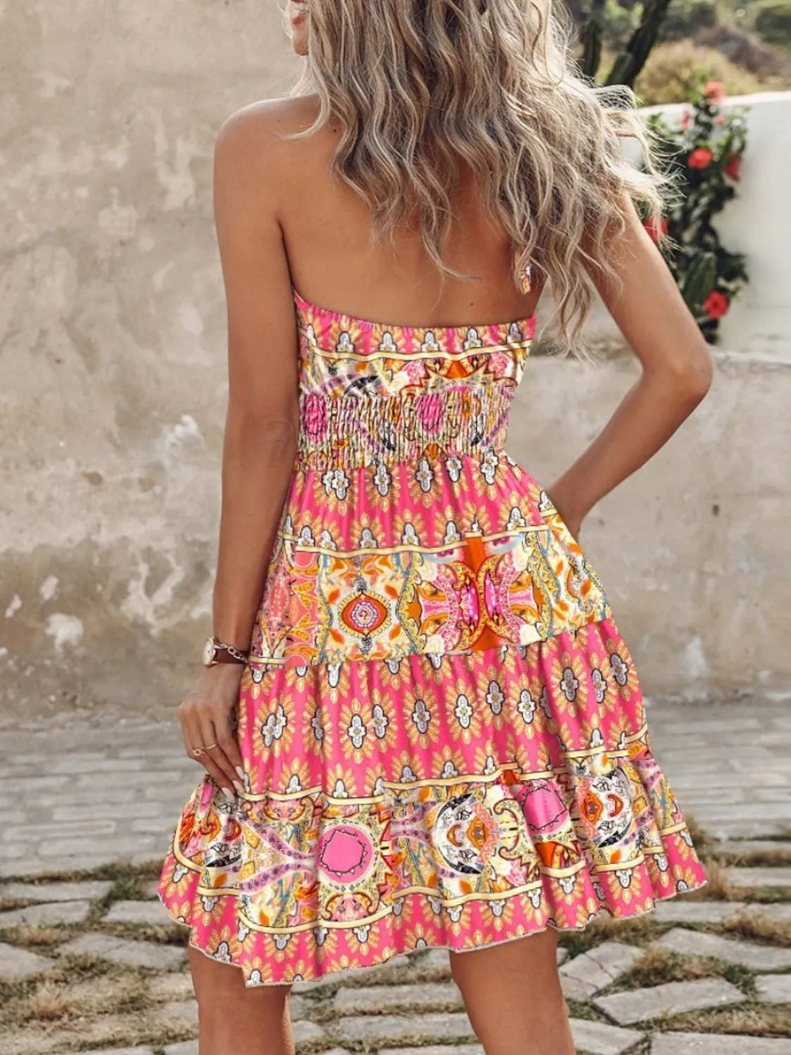 Woman wearing a colorful patterned dress with a neutral background