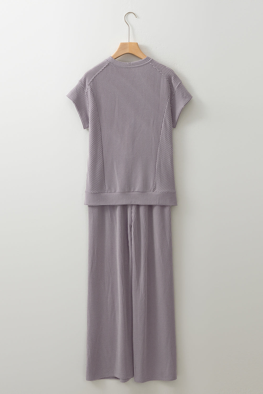 Purple ribbed knit outfit on a hanger against a white background