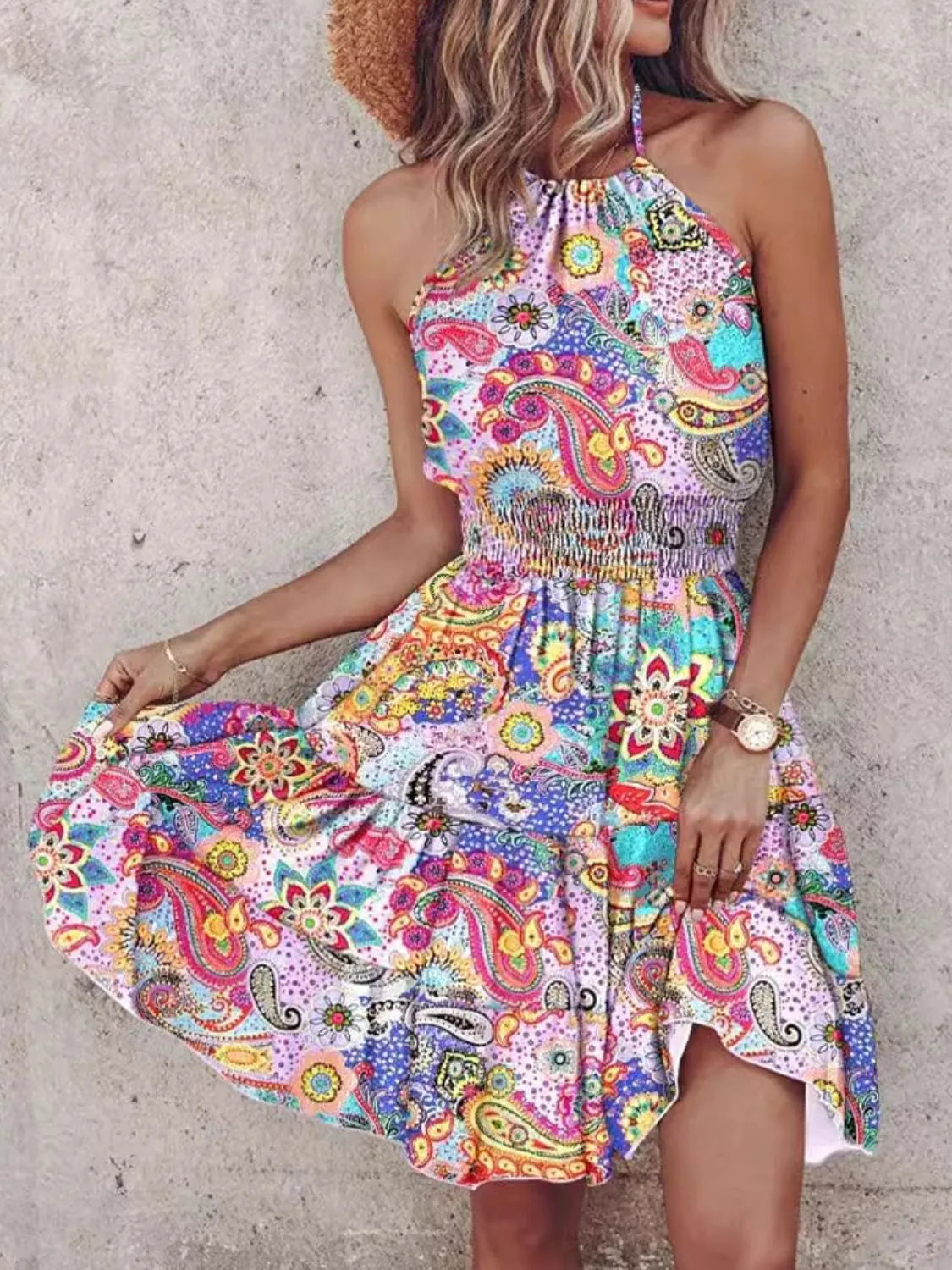 Woman wearing a colorful paisley dress against a plain background