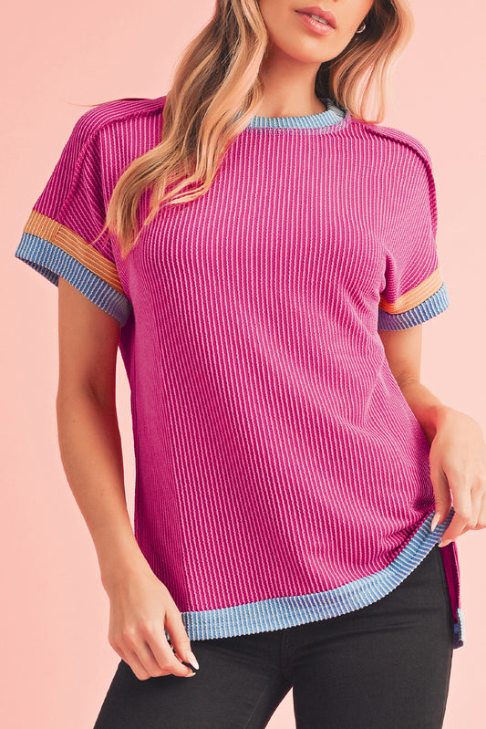 Woman wearing a pink ribbed knit top with colorful trim on a pink background