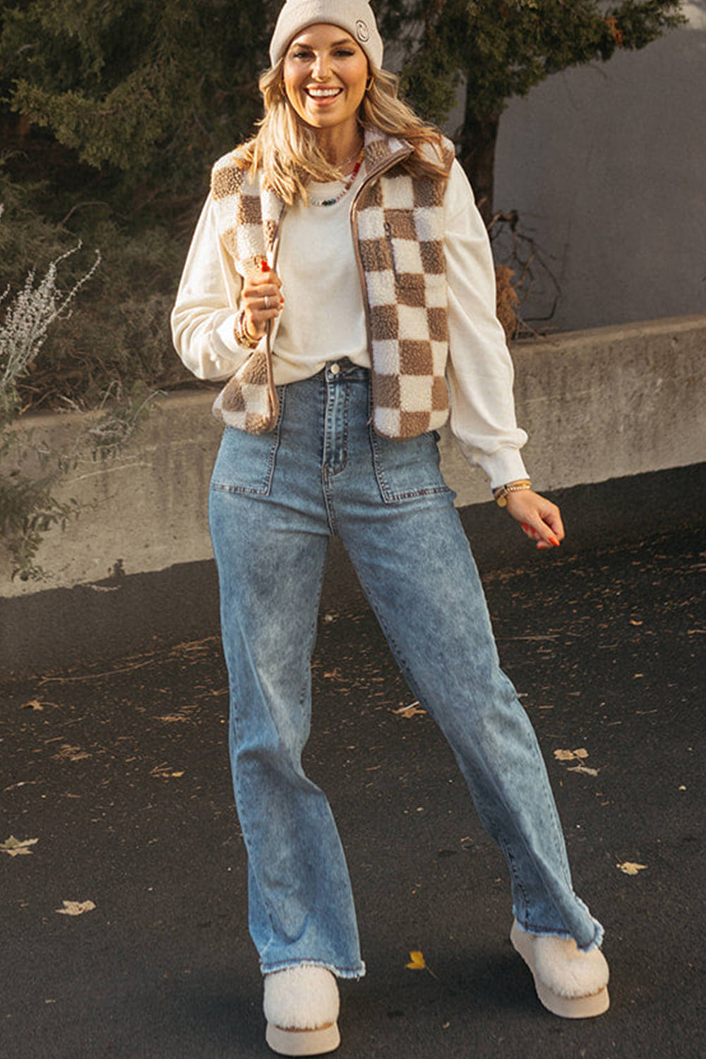 Woman wearing a plaid jacket, white shirt, blue jeans, and white sneakers outdoors.