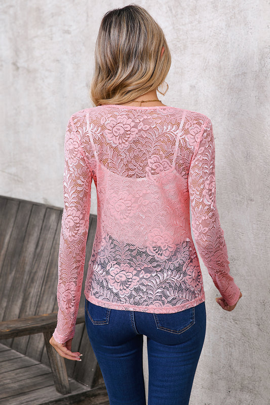 Person wearing a pink lace long-sleeve top and blue jeans against a neutral background