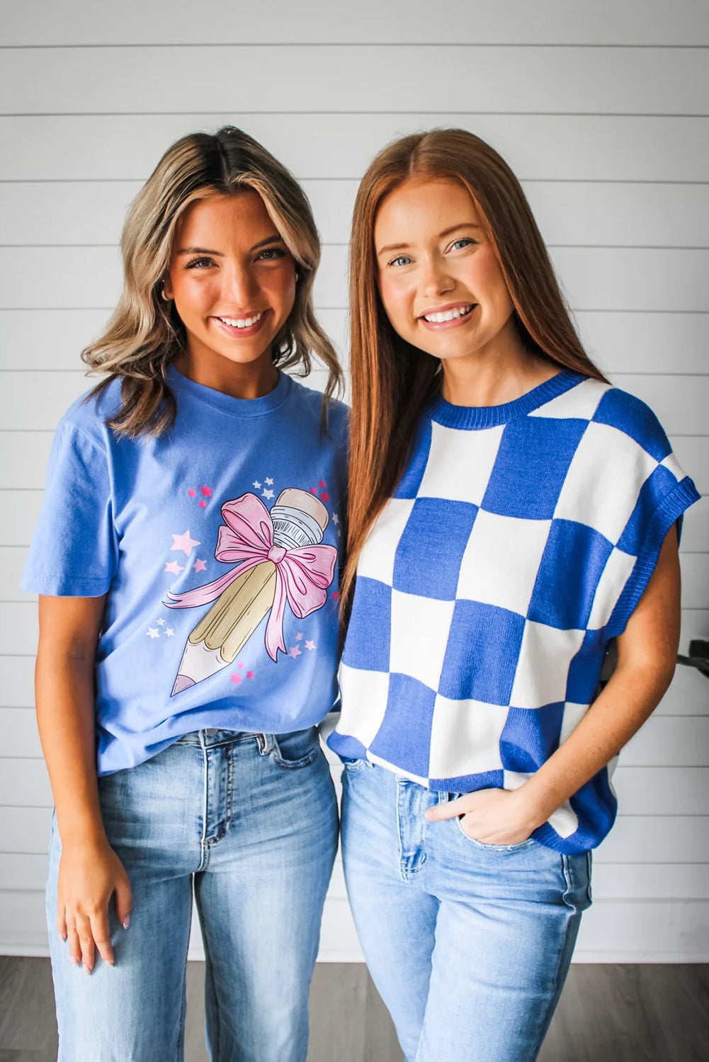 Two women standing side by side wearing blue and white checkered tops with a plain background