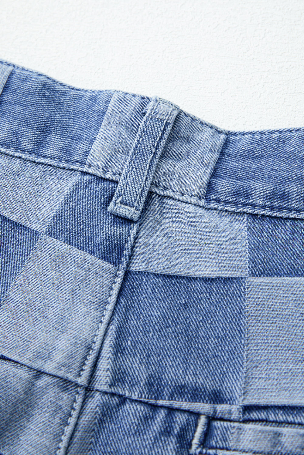 Close-up of blue denim fabric with a checkered pattern on a white background