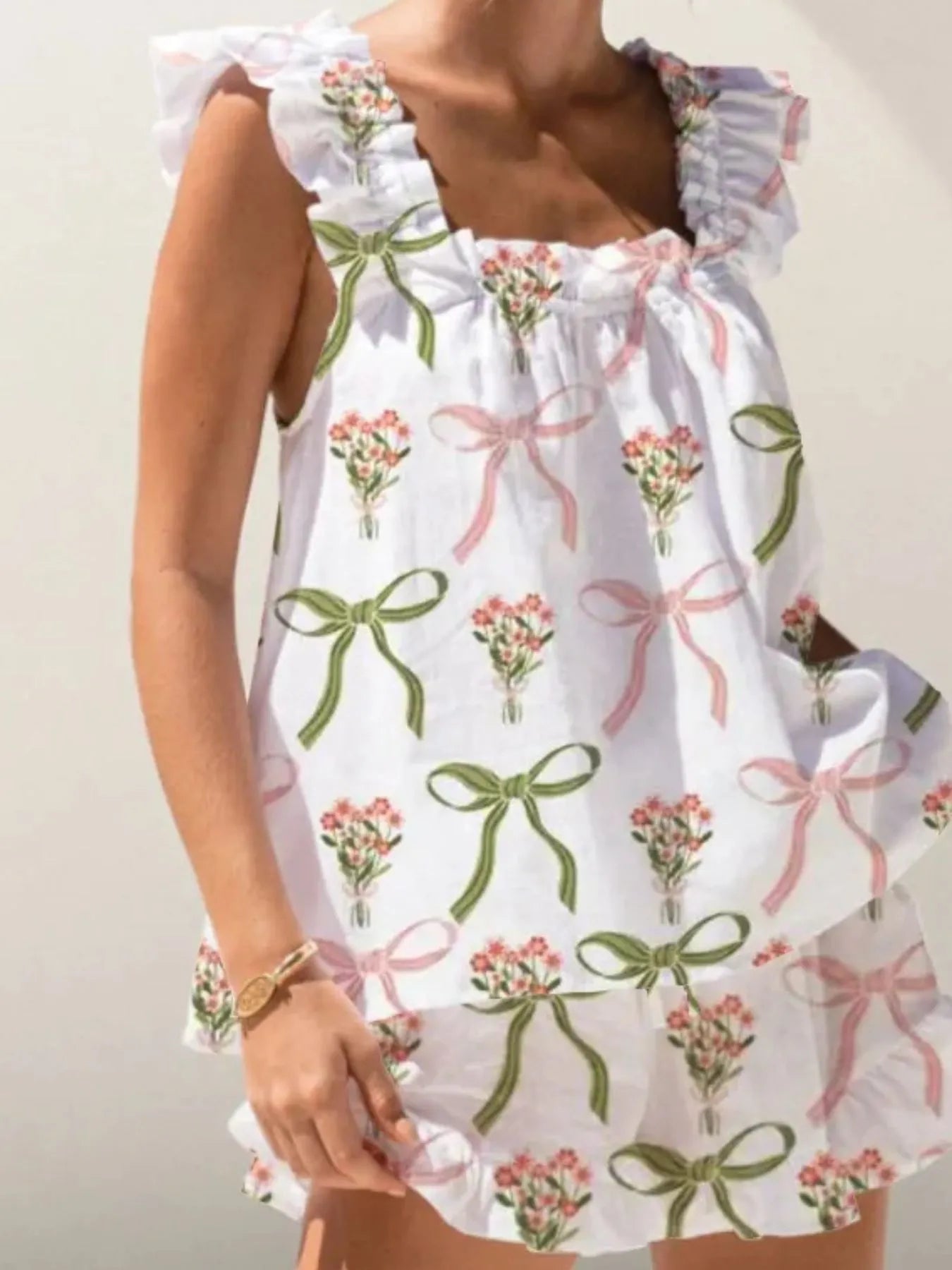 White dress with green bows and pink flowers on a plain background