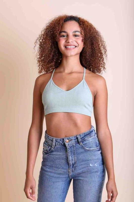 Woman wearing a light blue ribbed tank top and high-waisted jeans against a beige background