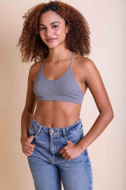 Woman wearing a gray ribbed crop top and blue jeans against a beige background