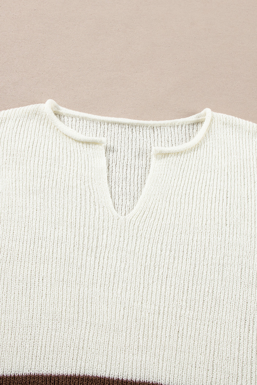 Close-up of a ribbed knit sweater with a V-neck on a beige background