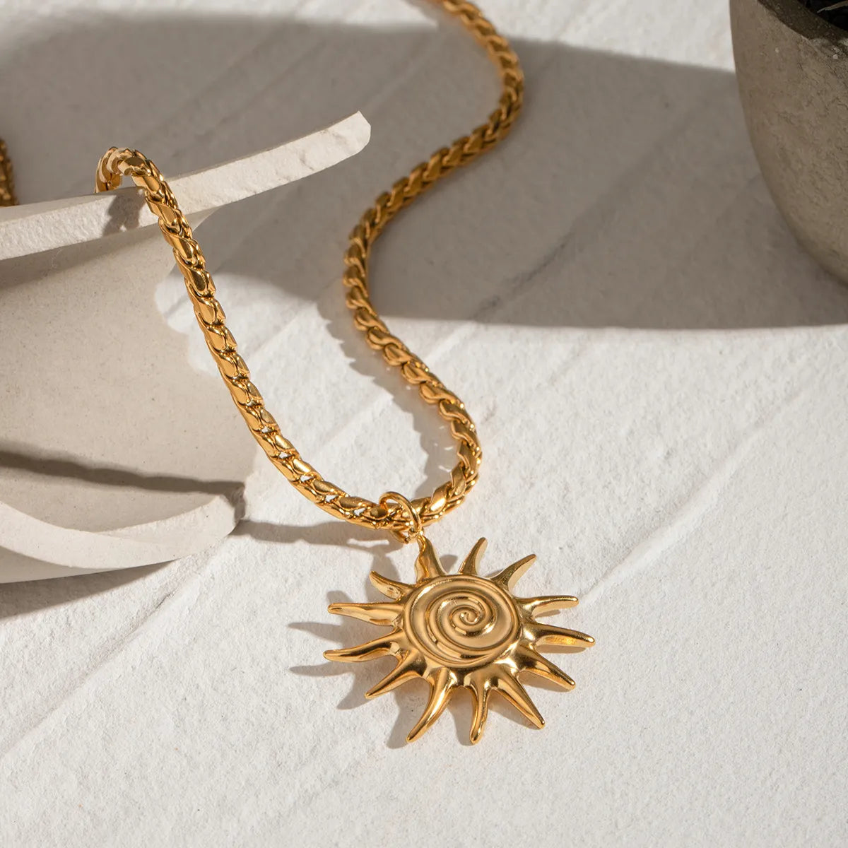 Gold necklace with a sun-shaped pendant on a white surface