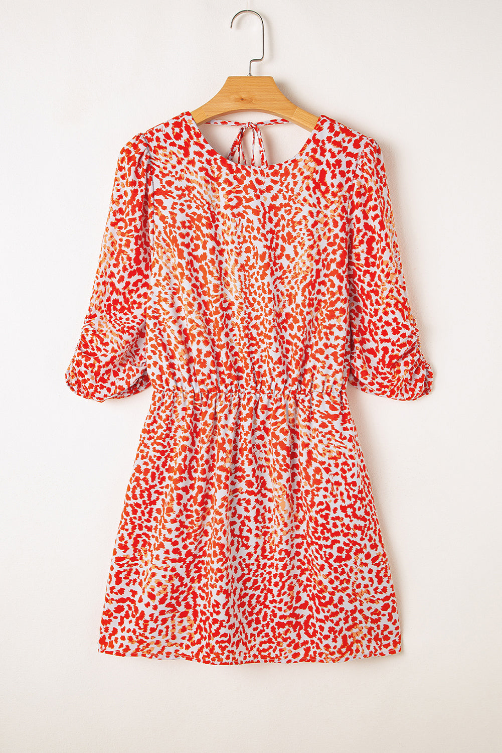 Red and white floral dress on a wooden hanger against a white background