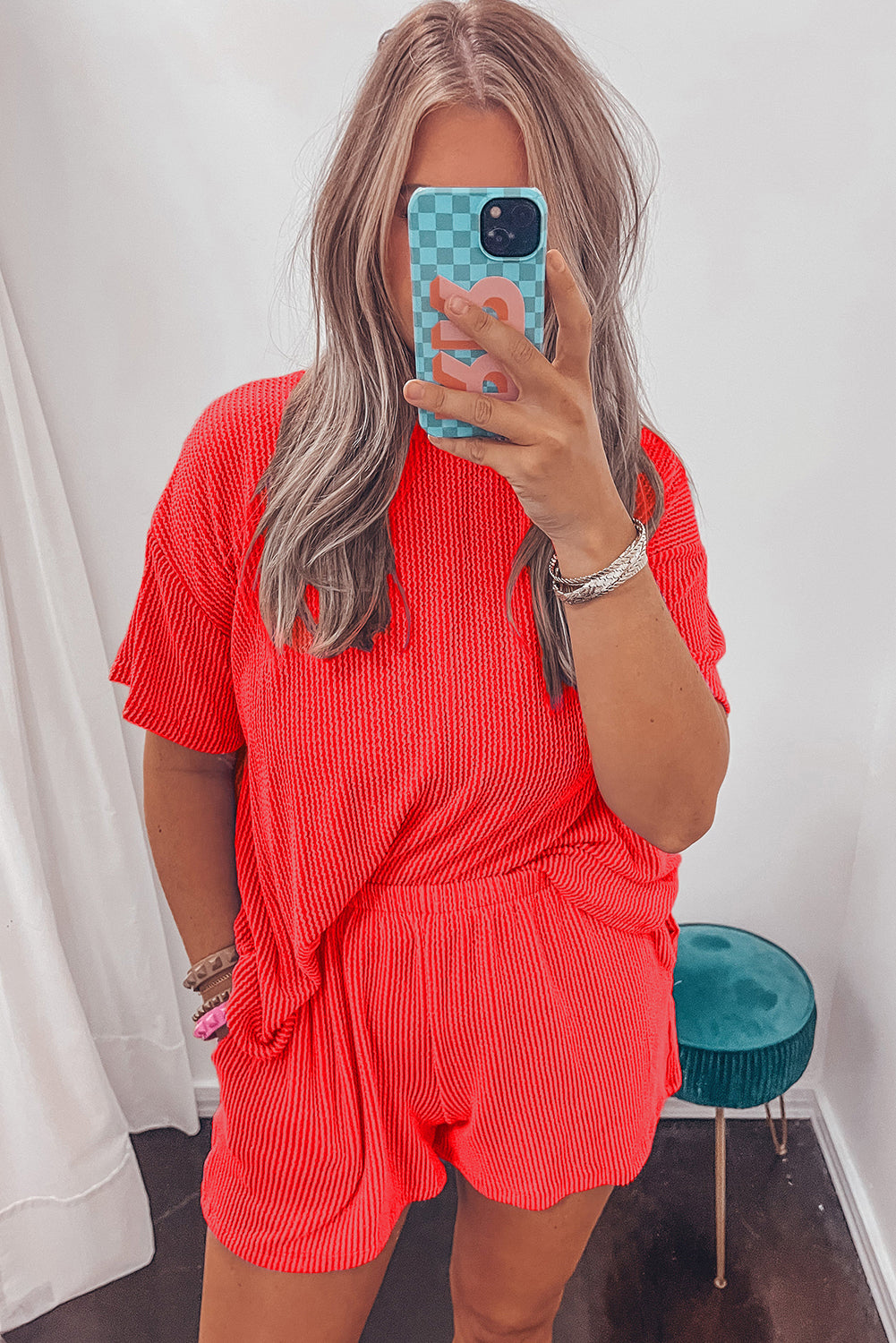 Person wearing a red ribbed outfit taking a mirror selfie.